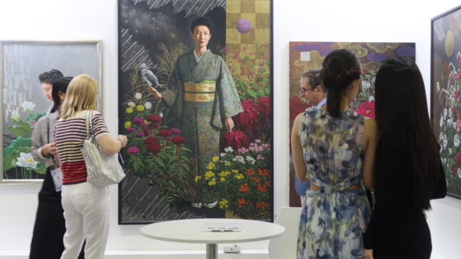 アートフェア会場のジャパンゾーンで、来場者が作品を見ている様子。人より大きなサイズの絵に、和服女性の全身と花が描かれている